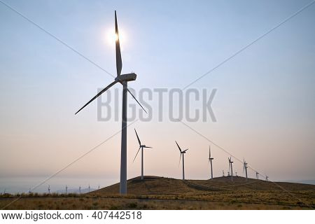 Windfarm Turbines In The Sun. Wind Turbines On An Arrid Field Of Grass In Washington State.