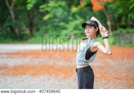 Portrait Of Runner Woman Doing Stretching And Warming Up Her Body Before Running In The Park. The Be