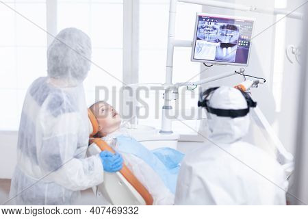 Little Girl In Ppe Looking At Her Mother In The Course Of Dental Examination. Stomatolog In Protecti