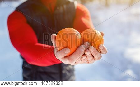 Closeup Of Fit Mature Man Holding Oranges As Healthy Snack After Morning Workout At Snowy Winter For