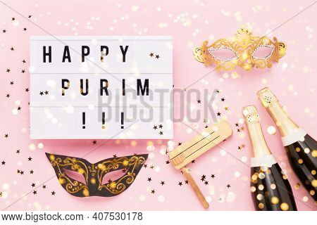 Flat Lay Of Purim Carnival Celebration Concept. Happy Purim Written In Light Box, Champagne Bottles,