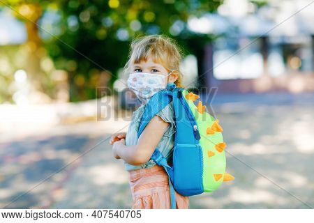 Little Toddler Girl On Her First Day On Way To Playschool With Medical Mask Against Corona Covid Vir