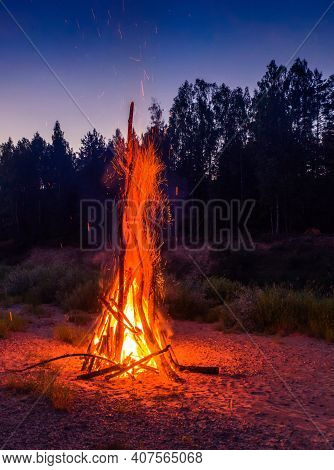 Traditional Midsummer Ligo Celebration In Latvia. Huge Bonfire. Scenic Landscape Of Forest At White