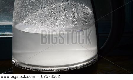 Turbid Water Inside Misted Glass Teapot With Shiny Drops In Bright Sunlight. Closeup Of Boiled Water