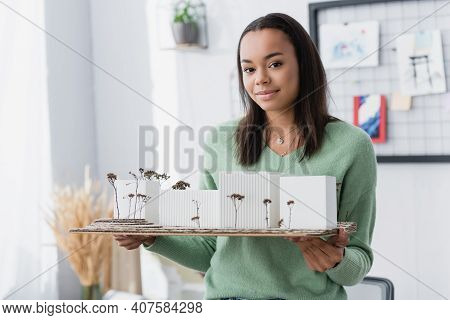 Smiling African American Woman Holding Architectural Maquette While Looking At Camera.
