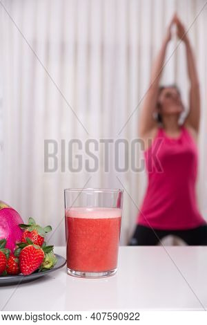 Green Smoothie With Focused Kiwis And Woman Exercising On Unfocused Background