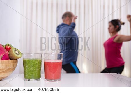 Green Smoothie With Focused Kiwis And Woman Exercising On Unfocused Background