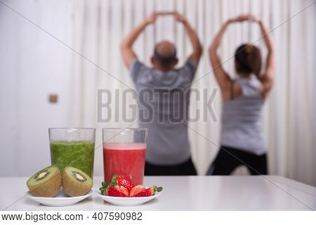 Green Smoothie With Focused Kiwis And Woman Exercising On Unfocused Background