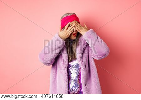 Fashion And Shopping Concept. Stylish Asian Hipster Granny In Purple Outfit Covering Her Eyes, Peeki