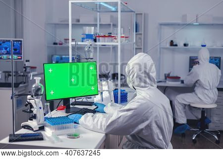 Doctor In Protection Suit Against Covid19 Delevoping Cure Using Computer With Green Screen Dressed I