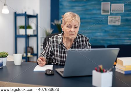 Senior Entrepreneur Reading From Portable Computer Without Glasses. Elderly Woman In Home Living Roo