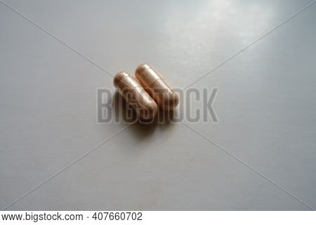 Close Shot Of Two Pink Capsules Of Probiotic Dietary Supplement