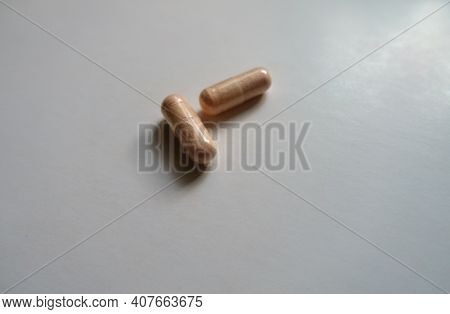 Two Pink Capsules Of Probiotic Dietary Supplement