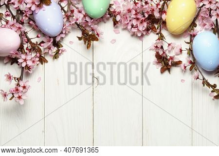 Eeaster Background With Cherry Blossom And Easter Eggs On Wooden Table. Space For Text.