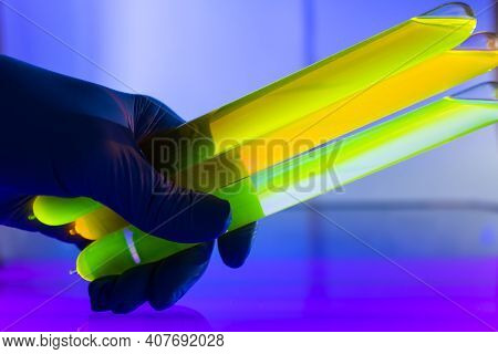 Fluorescein Glowing In Flask Under Ultraviolet Light. A Closeup Of Man Hand Holding Up A Vial  Fluor
