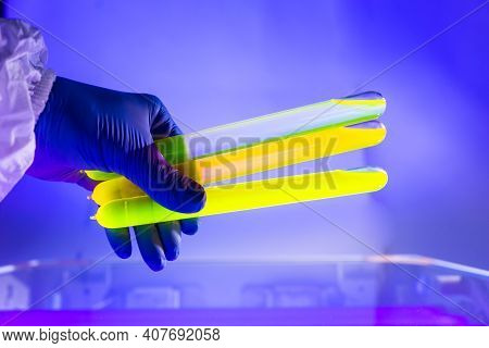 Fluorescein Glowing In Flask Under Ultraviolet Light. A Closeup Of Man Hand Holding Up A Vial  Fluor