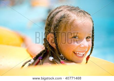 Smilyng bambina seduta su un anello gonfiabile in piscina.