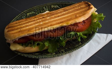 One Fresh Submarine Sandwich With Ham, Cheese, Tomatoes, Lettuce, Cucumbers In A Green Relief Plate