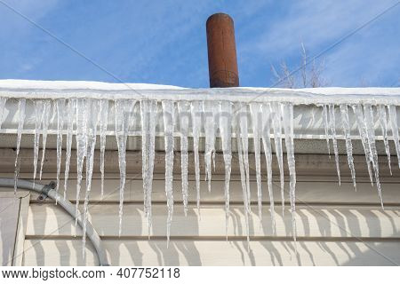 Frozen Gutters With Long Icicles Hanging From Ice Dams
