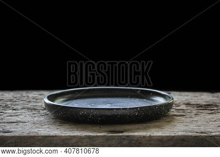 Empty Black Ceramics Plate And On Wooden Background.