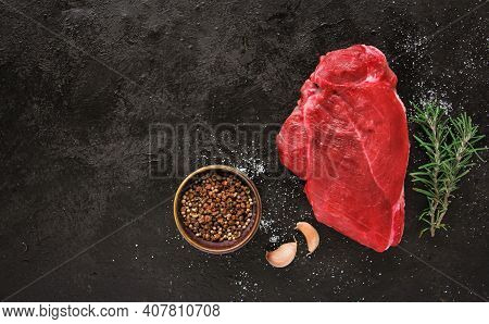 Raw Beef Steak With Spices On A Dark Slate, Stone Or Concrete Background. Top View With Copy Space.