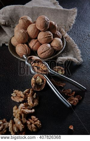 Walnuts On A Dark Background. Nutcracker For Walnuts. A Device For Cracking A Whole Nut. The Kernel