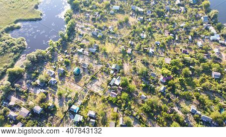Drone Fly Over Waving River Of Blue Color Surrounded By Local Village With Various Buildings And Wet