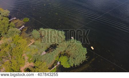 Drone Fly Over Waving River Of Blue Color Surrounded By Local Village With Various Buildings And Wet