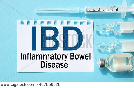 Ibd - Inflammatory Bowel Disease. Text On White Paper On A Blue Background. Ampoules, Syringe