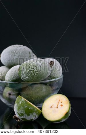 Iced Frozen Berries In Bowl. Many Whole Green Feijoa Berries With Cut One On Black Background. Prese