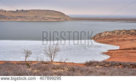 winter scenery of mountain lake at foothills of Rocky Mountains, partially frozen Horsetooth Reservoir - a popular recreational area in northern Colorado