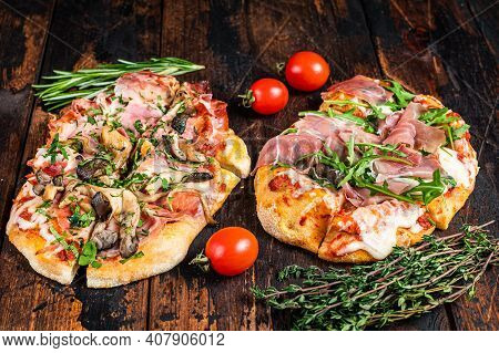 Sliced Pizza With Prosciutto Parma Ham, Arugula And Parmesan Cheese. Dark Wooden Background. Top Vie