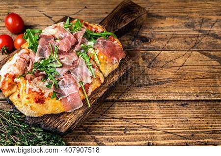 Sliced Pizza With Prosciutto Parma Ham, Arugula And Parmesan Cheese On A Wooden Board. Wooden Backgr