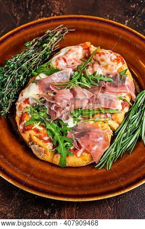 Pizza With Prosciutto Parma Ham, Arugula Salad And Parmesan Cheese In A Rustic Plate. Wooden Backgro