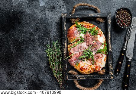 Italian Pizza With Prosciutto Parma Ham, Arugula Salad And Cheese In A Rustic Wooden Tray. Black Bac