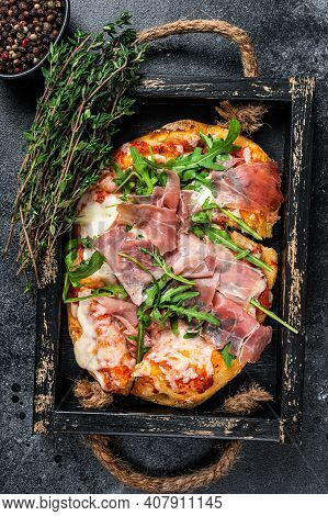Italian Pizza With Prosciutto Parma Ham, Arugula Salad And Cheese In A Rustic Wooden Tray. Black Bac