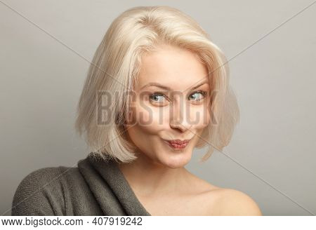 Close Up Attractive Blond Hair Woman With Cunning Smirk, Constrain Laugh, Isolated On Gray Backgroun