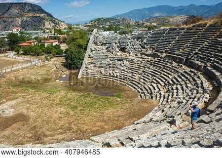 Tourist taking photo on ruins of Theatre in Letoon Ancient City in village Kumluova, Turkey. Sunny day, Greek culture ruins