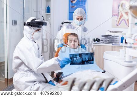Orthodontist In Ppe Suit Using Dental Radiography To Explain Dentistiry Procedure For Mouth Hygine. 