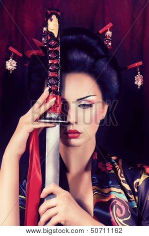 Beautiful geisha in kimono with samurai sword