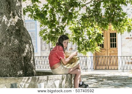 Girl With Straw Hat In Here Hands Sitting Under A Tree