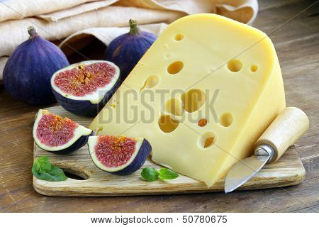 piece of cheese (Maasdam) with fresh figs on a wooden board