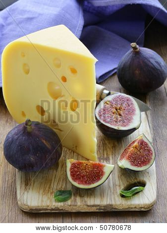piece of cheese (Maasdam) with fresh figs on a wooden board