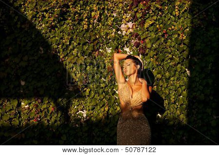 Beautiful Young Woman In Dress In Garden On Sunset