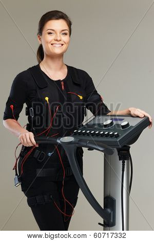 Young woman in training costume near Electro Muscular Stimulation EMS machine 