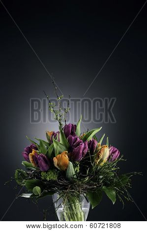 Bouquet of tulips in vase on dark background