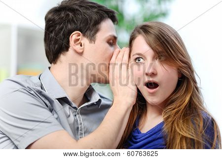 Man Whispering In The Ear Of His Surprised Wife