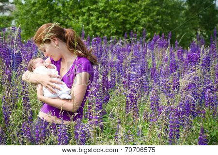 Young Mother With Her Newborn Baby In Purple Lupines Field