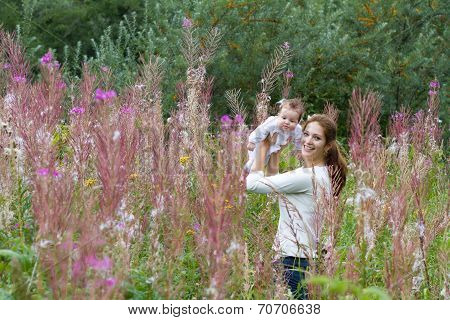 Beautiful Young Mother With A Baby Girl In Pink Flower Field
