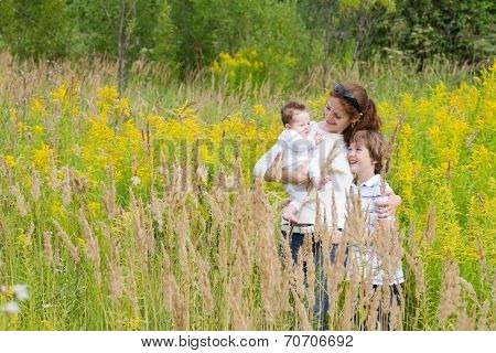Young Attractive Mother With Two Kids In A Yellow Flower Field